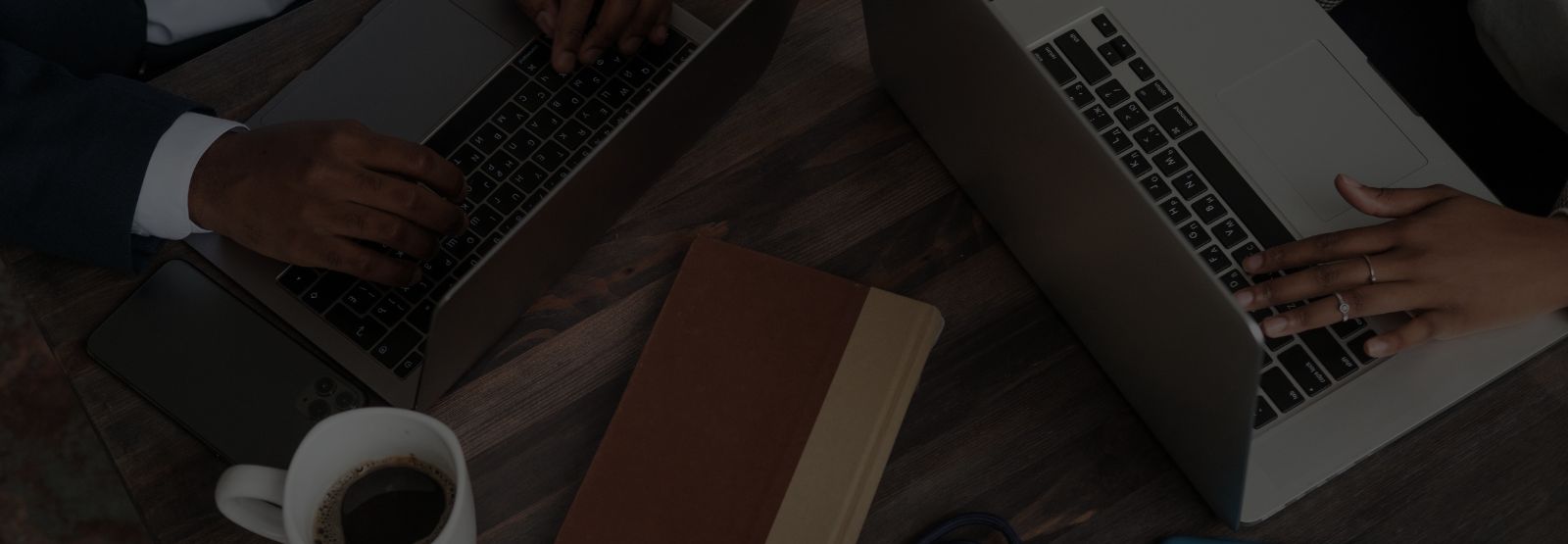 people working on laptops with a book and coffee on the table