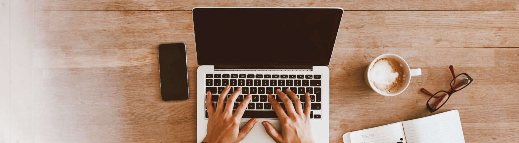 Typing at the computer with a coffee and notepad