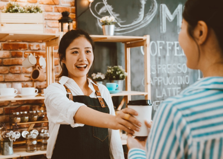 Woman handing customer a coffee at the coffee shop