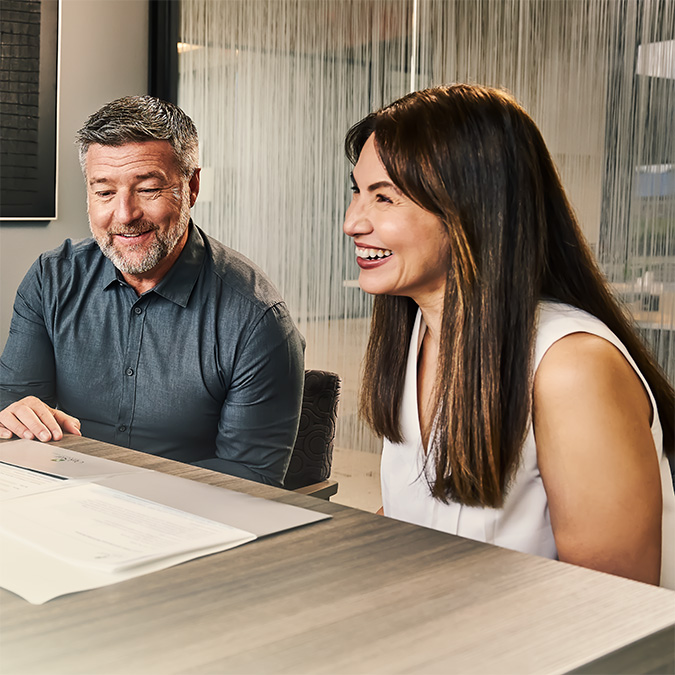 Two clients reviewing financial documents with a banker during a private banking consultation.