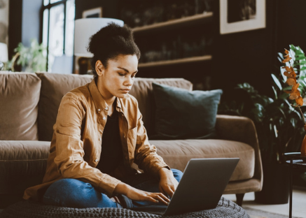 Woman using laptop on living room floor.