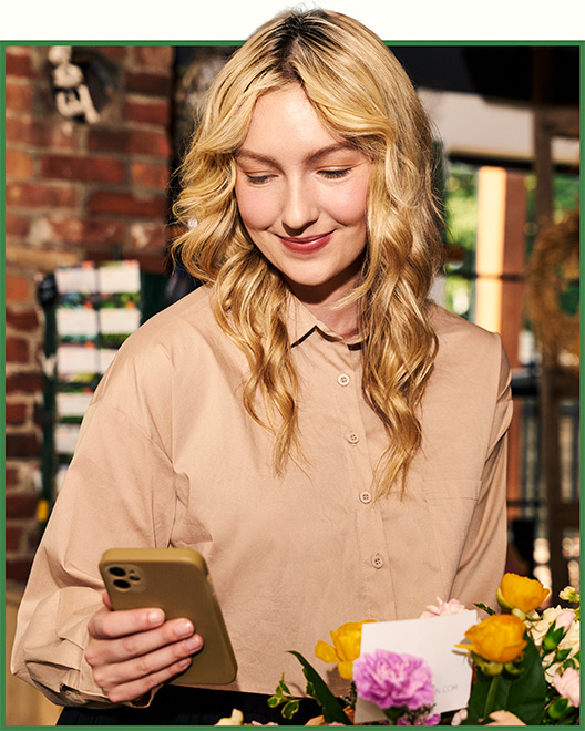 A customer using a smartphone to access mobile banking while working in a flower shop.