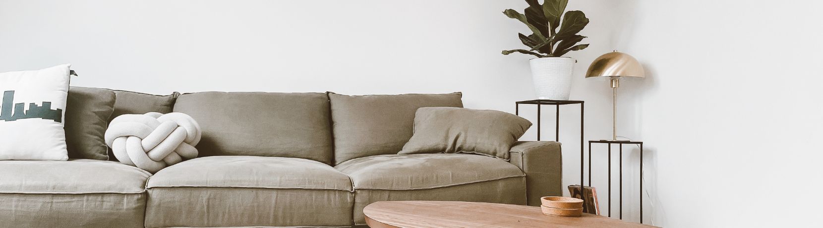 Couch with coffee table and two end tables with a plant and lamp
