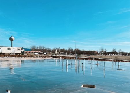 wet parking lot with water tower and blue skies in the background