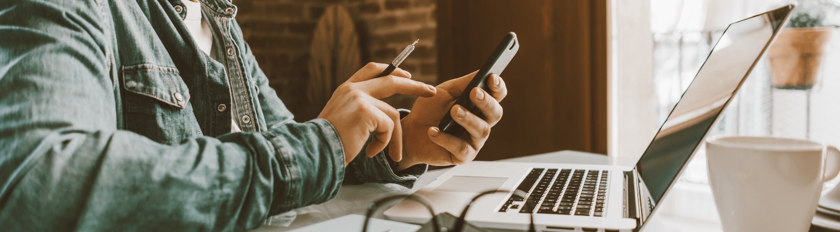 Man on his phone with his laptop in front of him