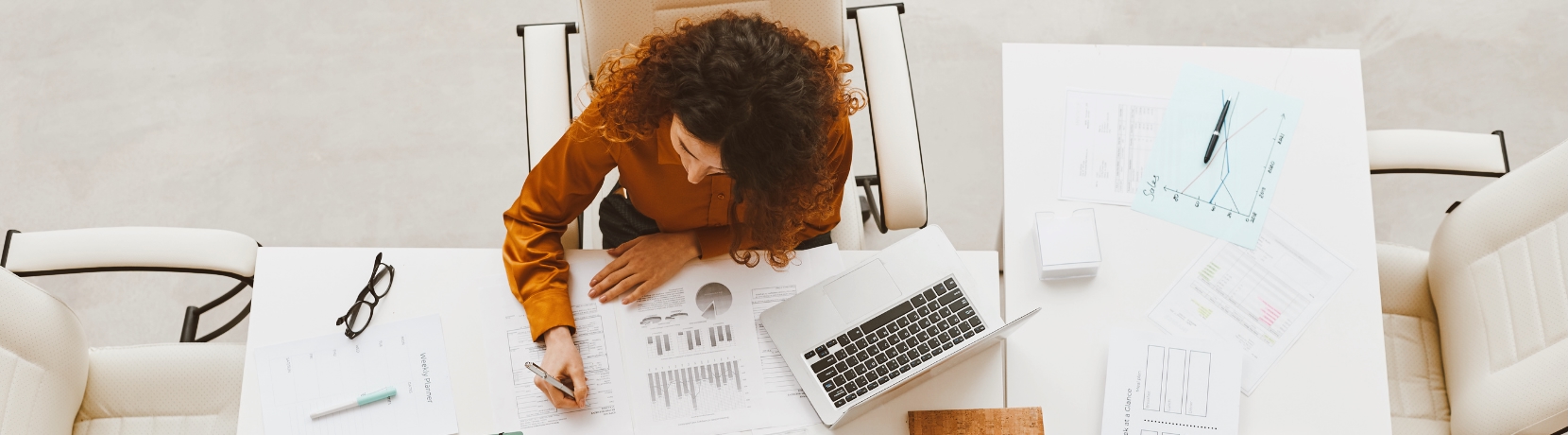 Woman working at her desk with documents and laptop