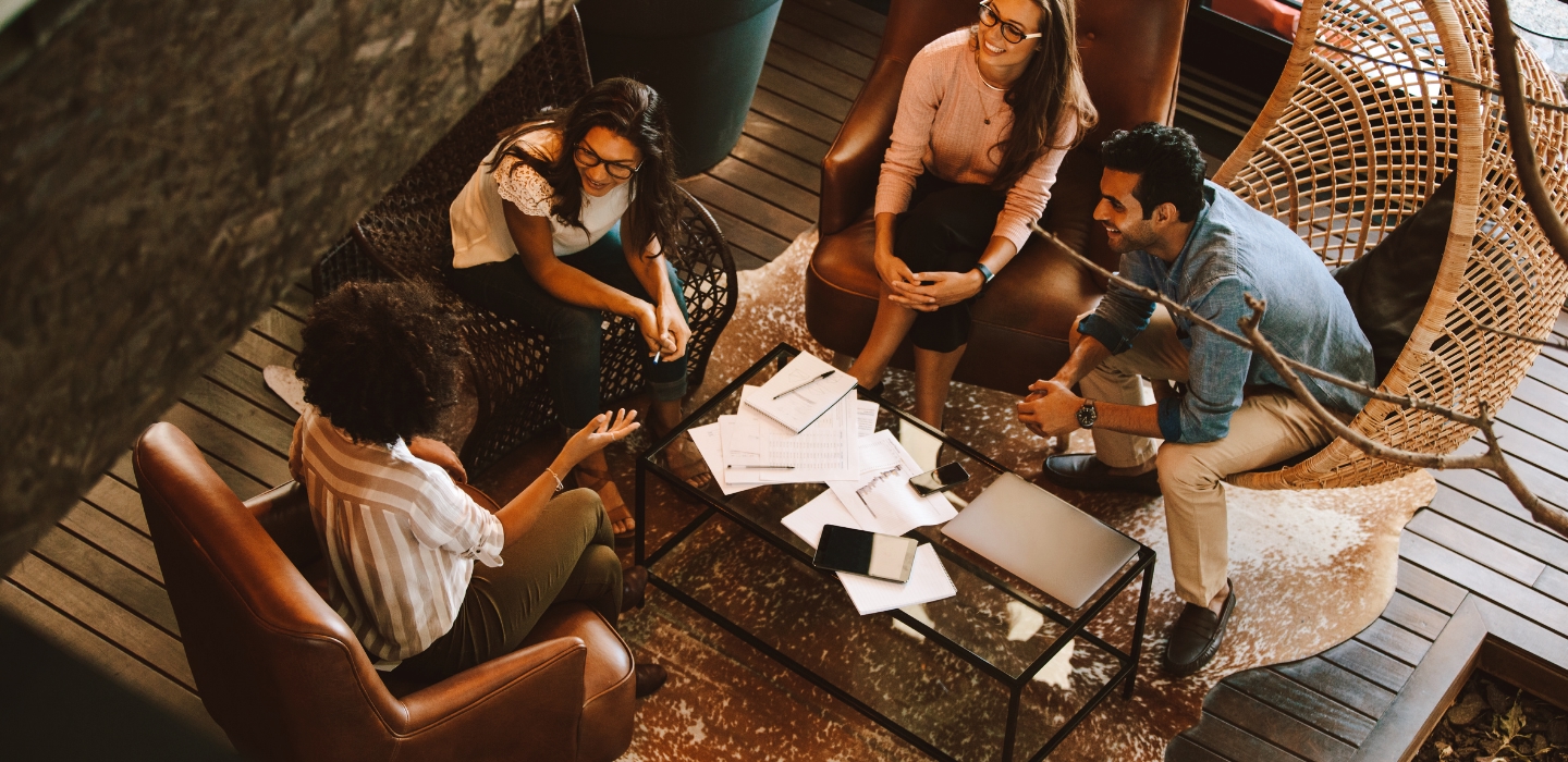 Group of women and man talking around a table about work.